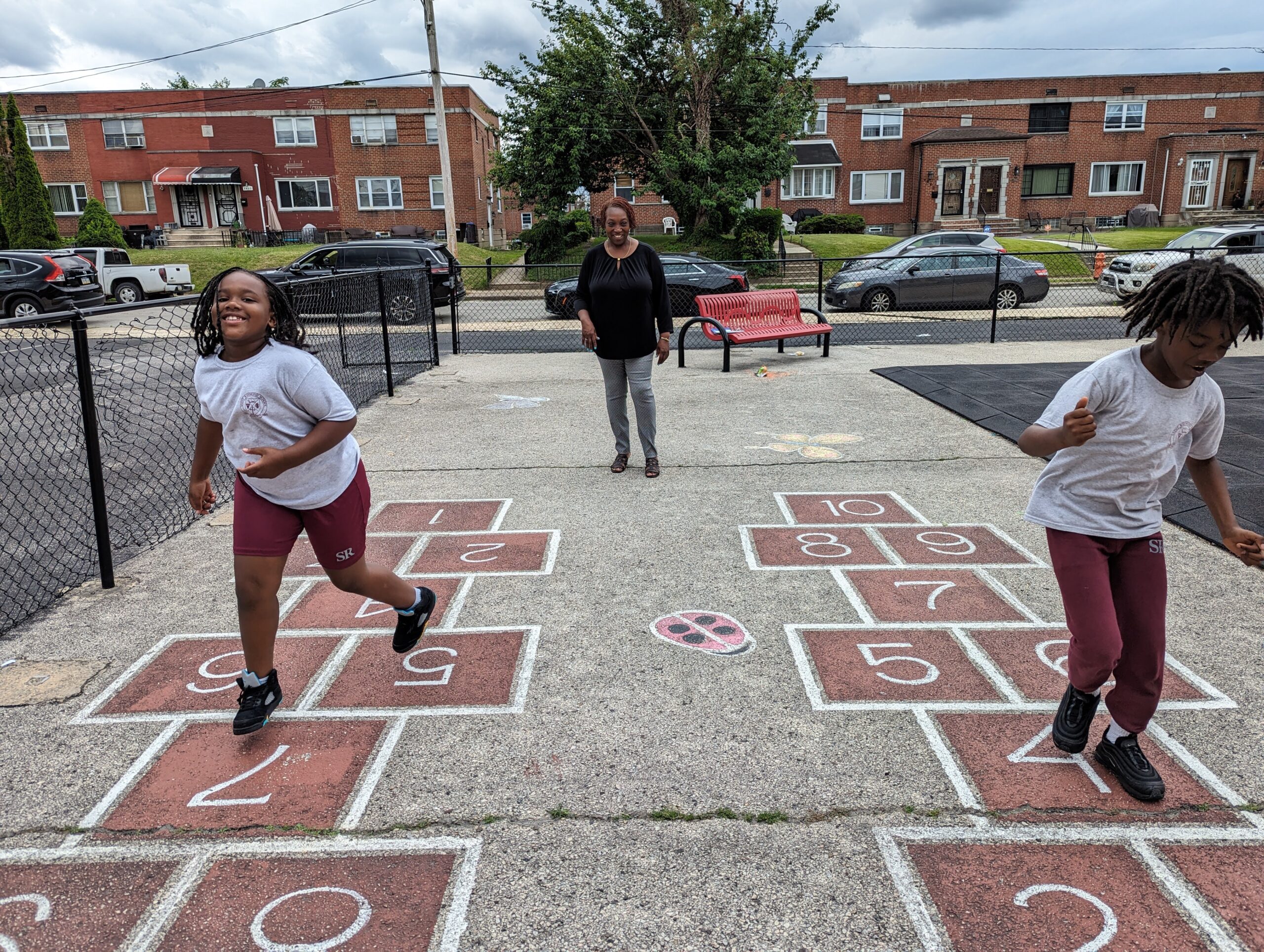 Students solving math problems through a hopscotch activity outdoors